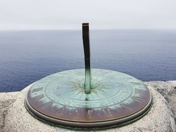 Close-up of metallic structure on sea against sky