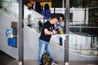 Man holding camera while standing by glass window