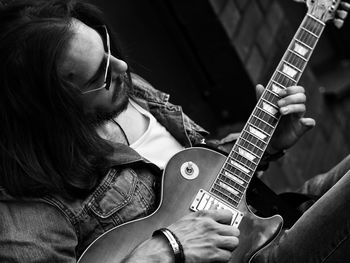 Bearded man playing guitar while sitting outdoors