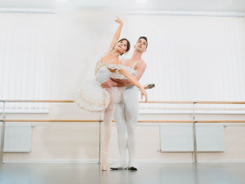 Full length of man and woman practicing ballet dance in studio