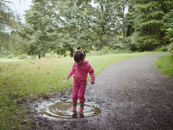 Full length of girl standing in puddle on road