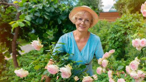 Portrait of smiling senior woman with pink flowers at garden