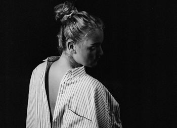 Rear view of woman wearing shirt against black background