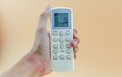 Close-up of hand holding camera against gray background