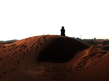 Silhouette man on desert against clear sky