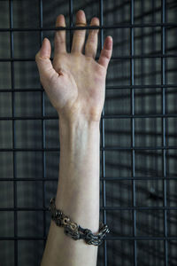 Close-up of human hand tied with chain on fence