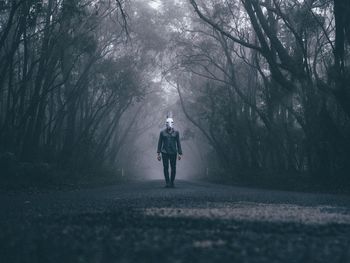 Man wearing rabbit mask on forest road