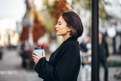 Side view portrait of a young woman using phone