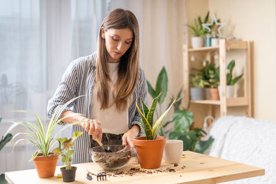 Woman gardeners taking care and transplanting plant a into a new ceramic pot . home gardening