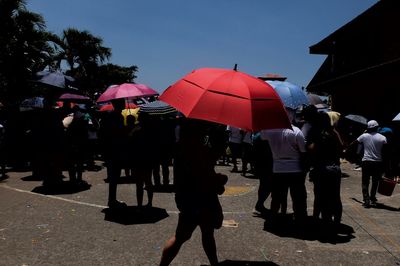 People on sidewalk in city against clear sky