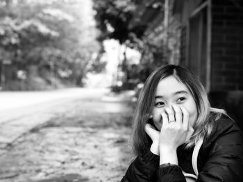 Young woman covering mouth while looking away outdoors