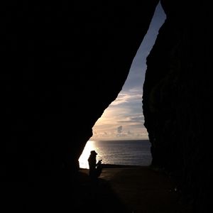 Silhouette man standing by sea against sky during sunset