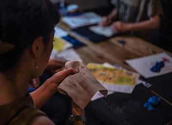 Midsection of woman making embroidery on fabric