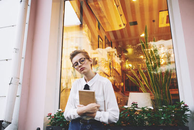 Portrait of young man looking through window