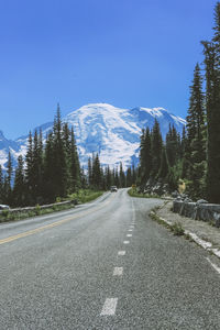 Road amidst trees and mountains against sky