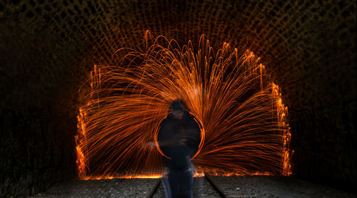 Rear view of man with umbrella standing at night