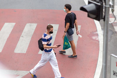 Rear view of friends walking on street in city