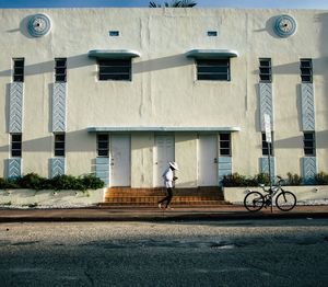 Man running on footpath against building in city