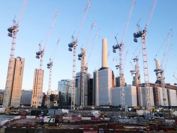 Panoramic view of cranes and buildings against sky