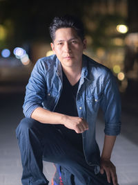 Portrait of young man sitting on street