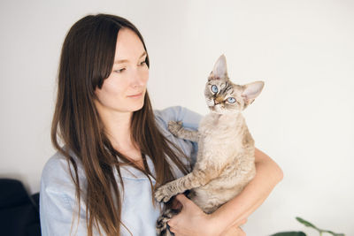 Portrait of young woman with cat against white background