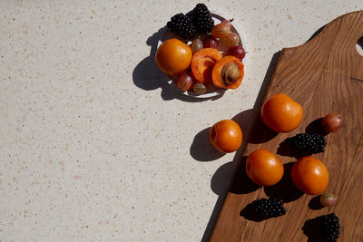 Fresh healthy summer fruits and berries - apricots, gooseberry and blackberry under hard shadows. 