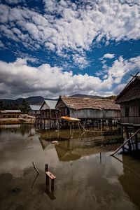 Man standing on lake by building against sky