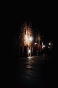 Illuminated street amidst buildings against clear sky at night