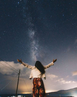 Low angle view of woman standing against sky at night