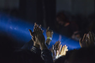 People clapping while enjoying music concert at night