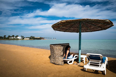 Deck chairs on beach against sky