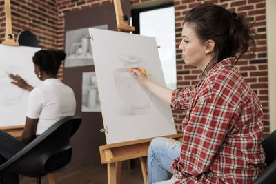 Side view of young woman using laptop while sitting in office