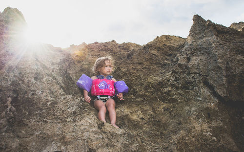 Portrait of girl on rock against sky