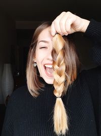 Portrait of smiling young woman holding braided cut hair