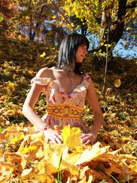 Young woman standing by leaves during autumn