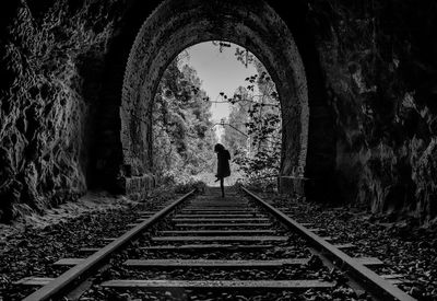 Rear view of so man standing on railroad tracks in tunnel