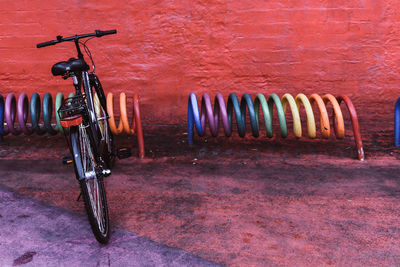 Bicycle parked against red wall