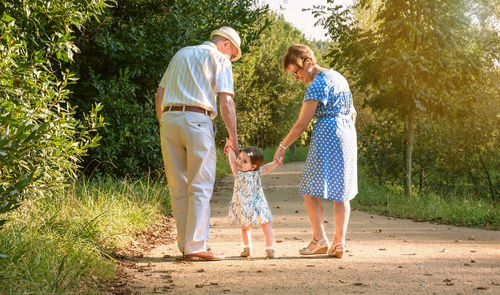 Rear view of grandparents walking with granddaughter at park