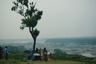 People standing on landscape against clear sky