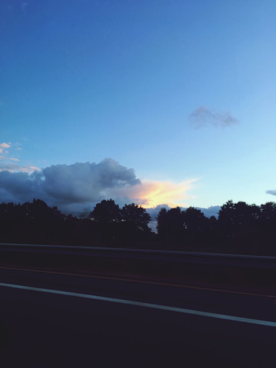 SILHOUETTE TREES BY ROAD AGAINST BLUE SKY