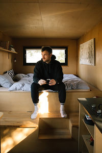 Young man sitting on hardwood floor at home