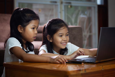 Siblings using laptop at desk