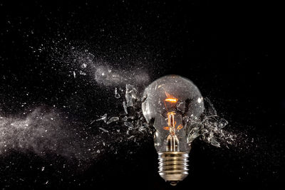 Close-up of broken light bulb against black background