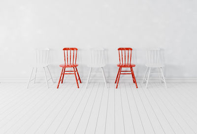 Empty chairs against white wall
