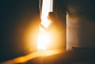 Low angle view of silhouette woman standing by window