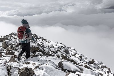 Rear view of man standing on snow against sky