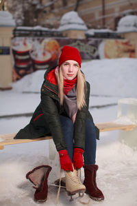 Young blond woman putting on ice scates outdoor ice rink