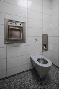 Interior of new and modern clean public restroom with white tiles and stainless steel bowl