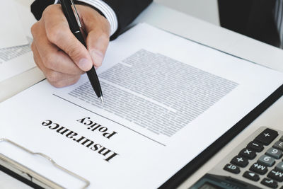 Midsection of man reading book on table
