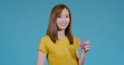 Portrait of a smiling young woman against blue background